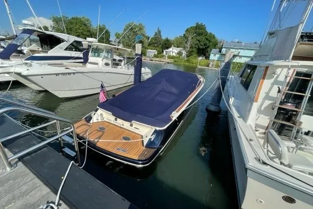  Yacht Photos Pics 2017 Chris-Craft Corsair 32 docked, covered with a navy blue tarp, surrounded by other boats.