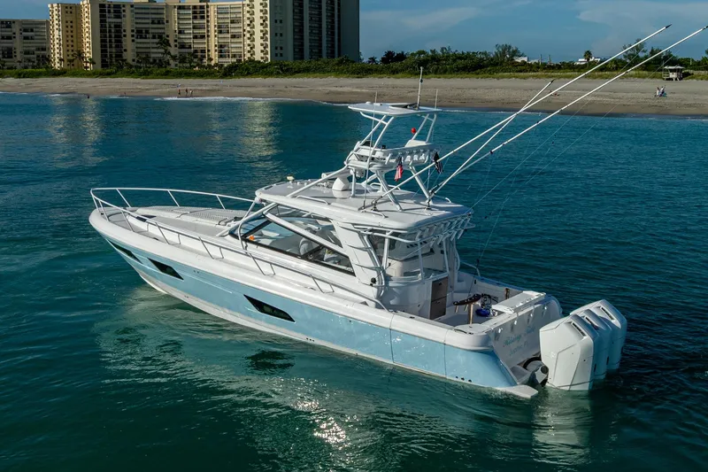Rising Tide Yacht Photos Pics 2023 Intrepid 477 Evolution boat cruising near a beach with buildings in the background.