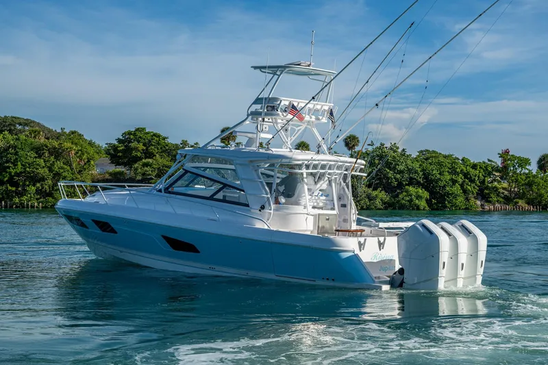 Rising Tide Yacht Photos Pics 2023 Intrepid 477 Evolution boat cruising on clear blue water near lush greenery.