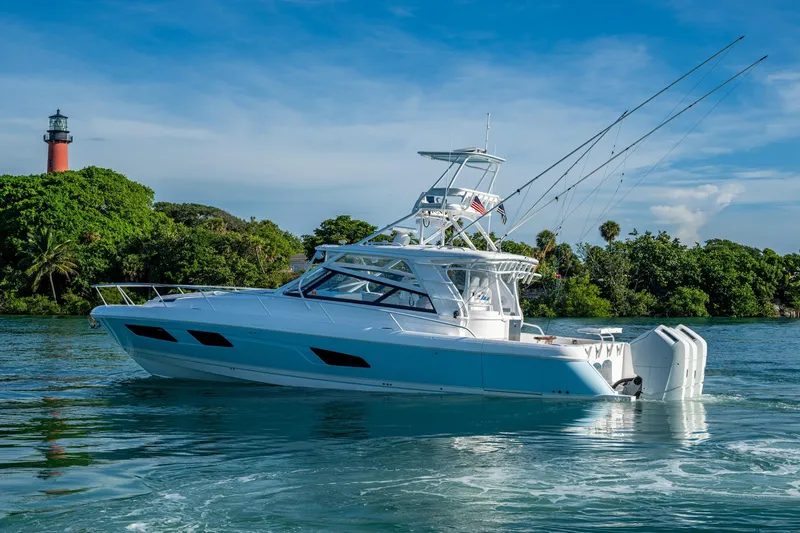 Rising Tide Yacht Photos Pics 2023 Intrepid 477 Evolution yacht cruising near a lighthouse and lush greenery.