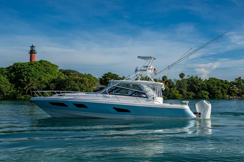 Rising Tide Yacht Photos Pics 2023 Intrepid 477 Evolution yacht cruising near a lighthouse and lush greenery.