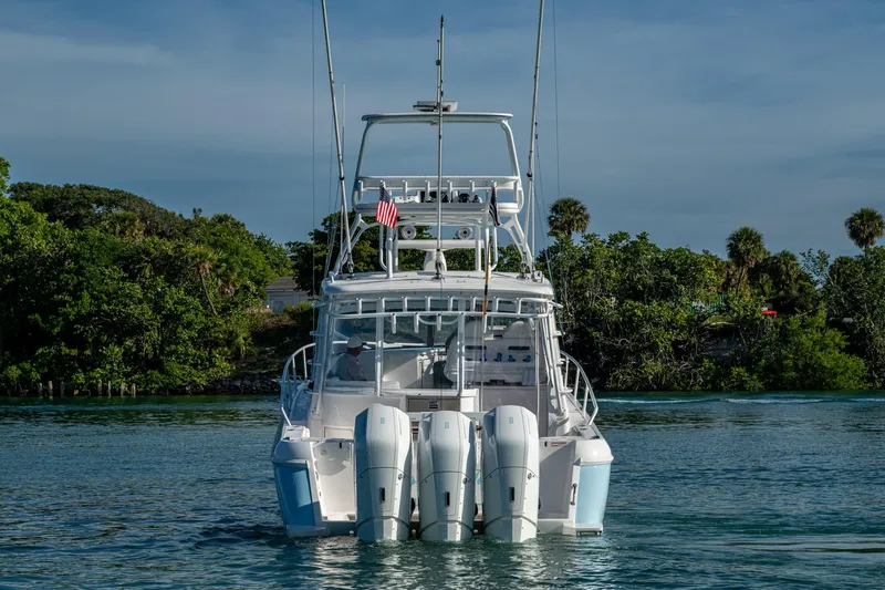 Rising Tide Yacht Photos Pics 2023 Intrepid 477 Evolution boat on water, rear view with lush greenery background.