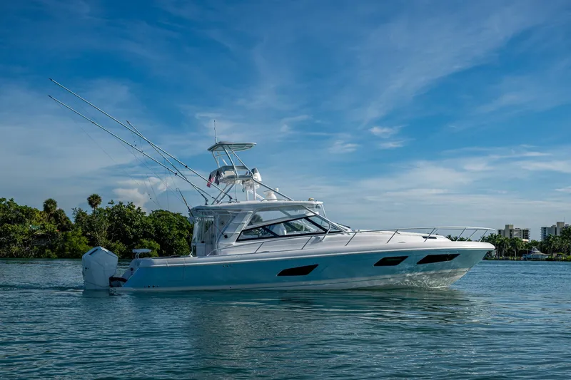 Rising Tide Yacht Photos Pics 2023 Intrepid 477 Evolution boat cruising on a sunny day, surrounded by lush greenery.