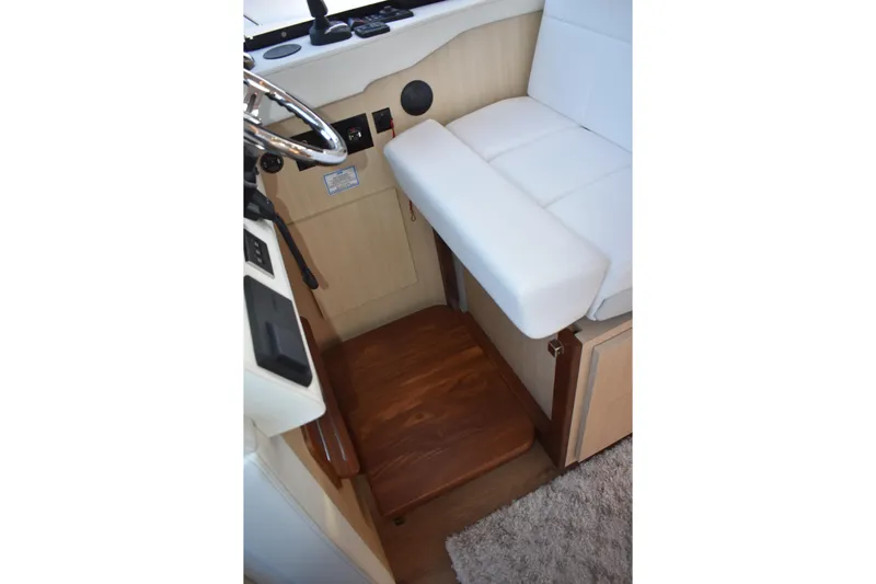  Yacht Photos Pics 2025 Regal 38 FXO helm seat with white upholstery and wooden flooring.