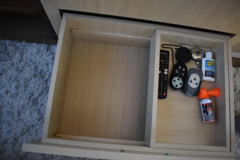  Yacht Photos Pics Open drawer with remote controls, cleaning supplies, and accessories on a Regal 38 FXO 2025.