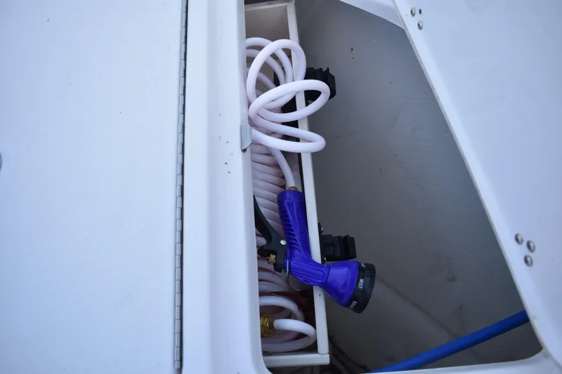  Yacht Photos Pics Storage compartment with coiled hose and spray nozzle on 2025 Regal 38 FXO boat.
