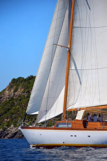 Tre C Ex Naly Yacht Photos Pics 1971 Sangermani Ketch sailing near rocky coastline under clear blue sky.