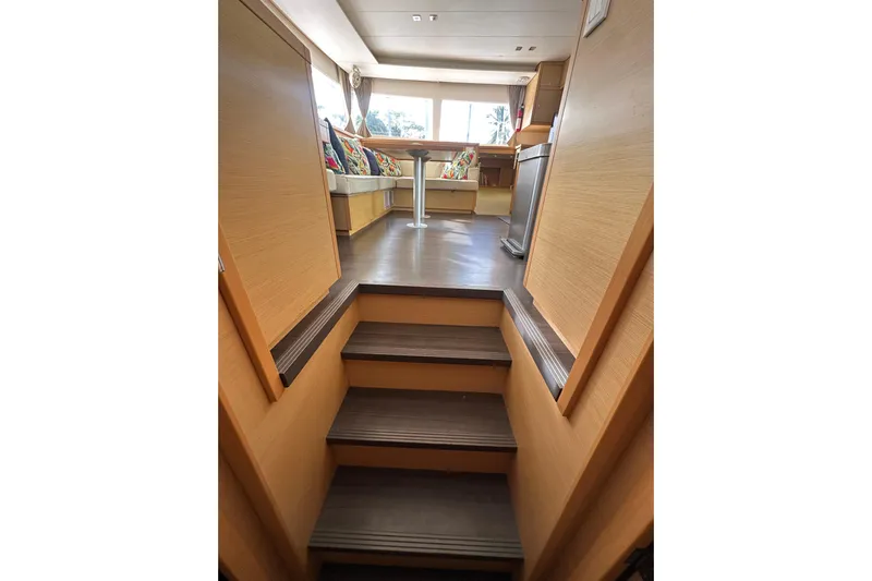 Callisto Yacht Photos Pics Interior view of 2014 Lagoon 450 F yacht, featuring wooden stairs and a cozy seating area.