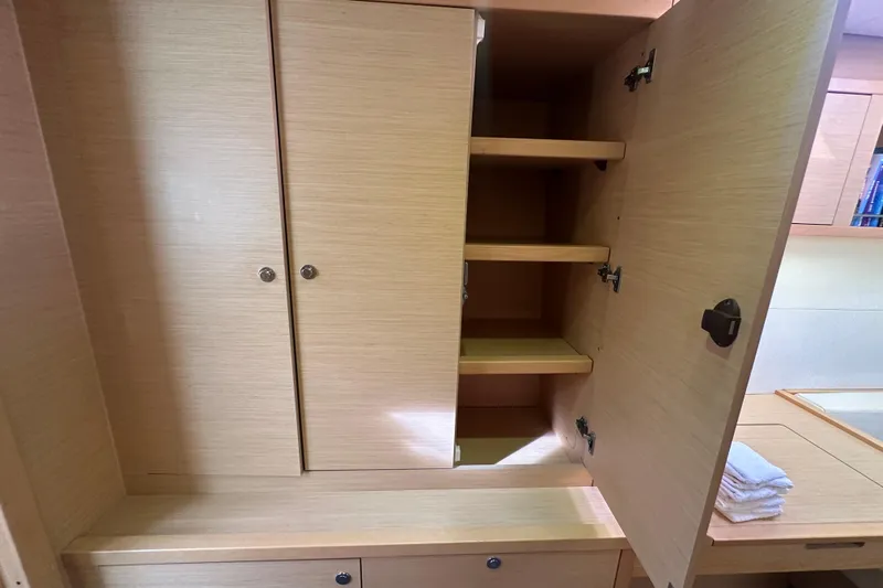Callisto Yacht Photos Pics Open wooden cabinet with shelves inside a 2014 Lagoon 450 F yacht interior.