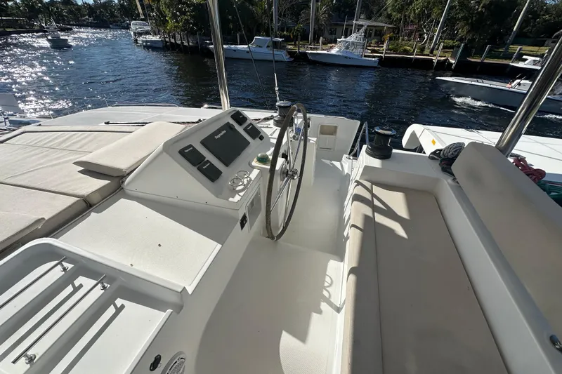 Callisto Yacht Photos Pics Cockpit of 2014 Lagoon 450 F catamaran with steering wheel and seating, docked by a river.