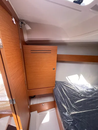  Yacht Photos Pics 2023 Dufour 32 yacht interior cabin with wooden cabinetry and bed.