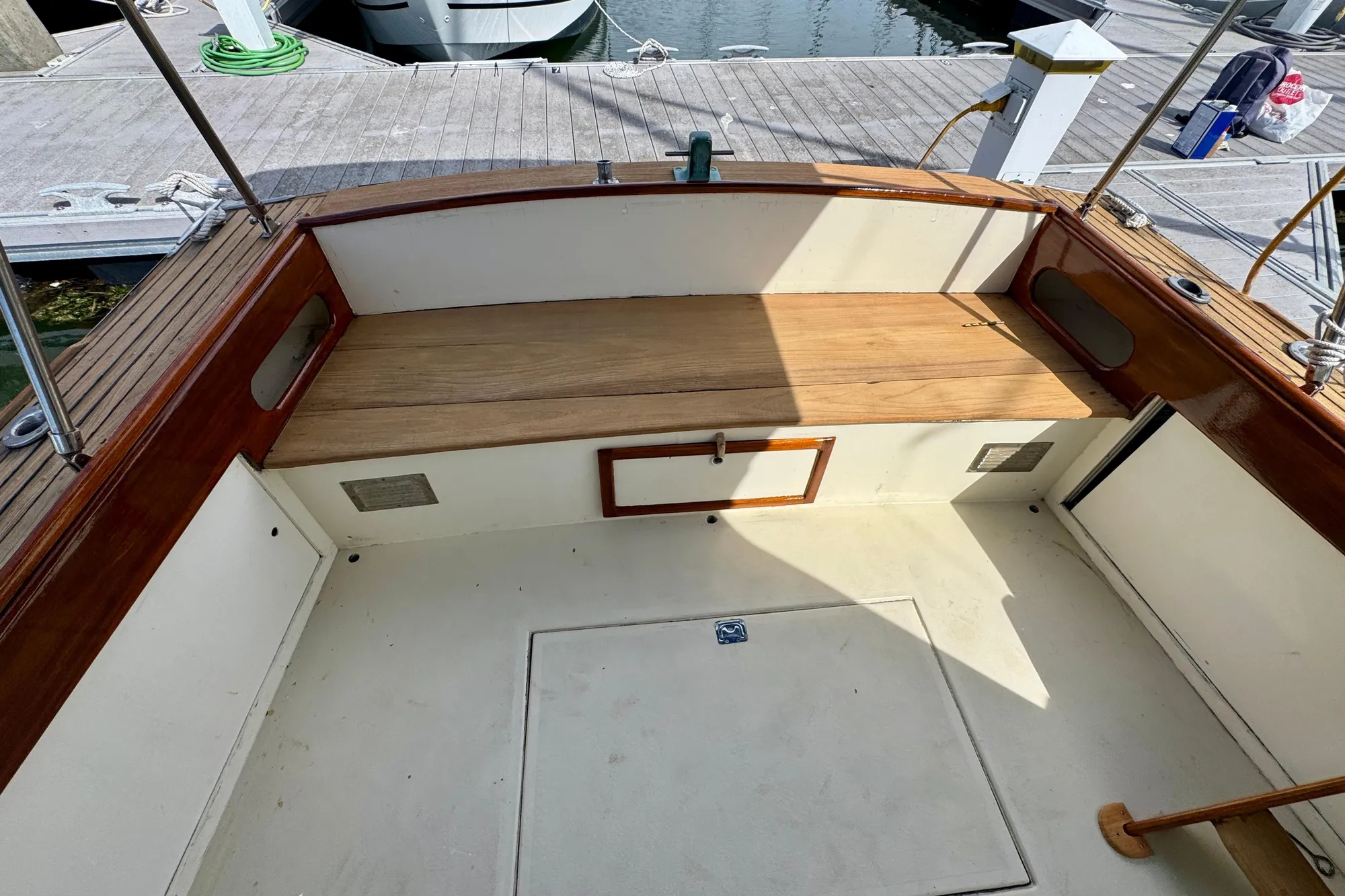 1982 Jarvis Newman Flybridge Cruiser cockpit with wooden bench and storage, docked at marina.