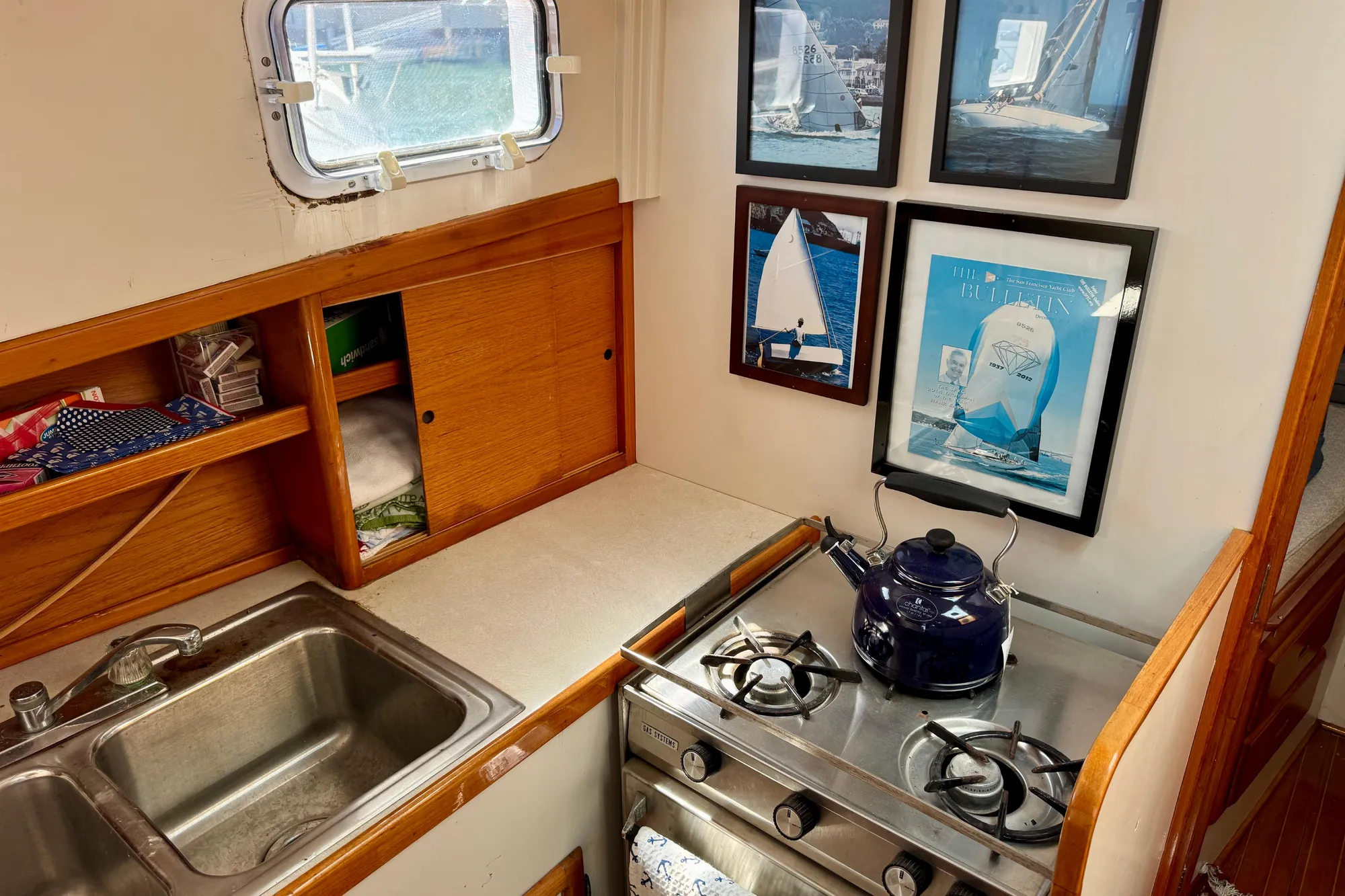 1982 Jarvis Newman Flybridge Cruiser kitchen with stove, sink, and sailing-themed wall art.