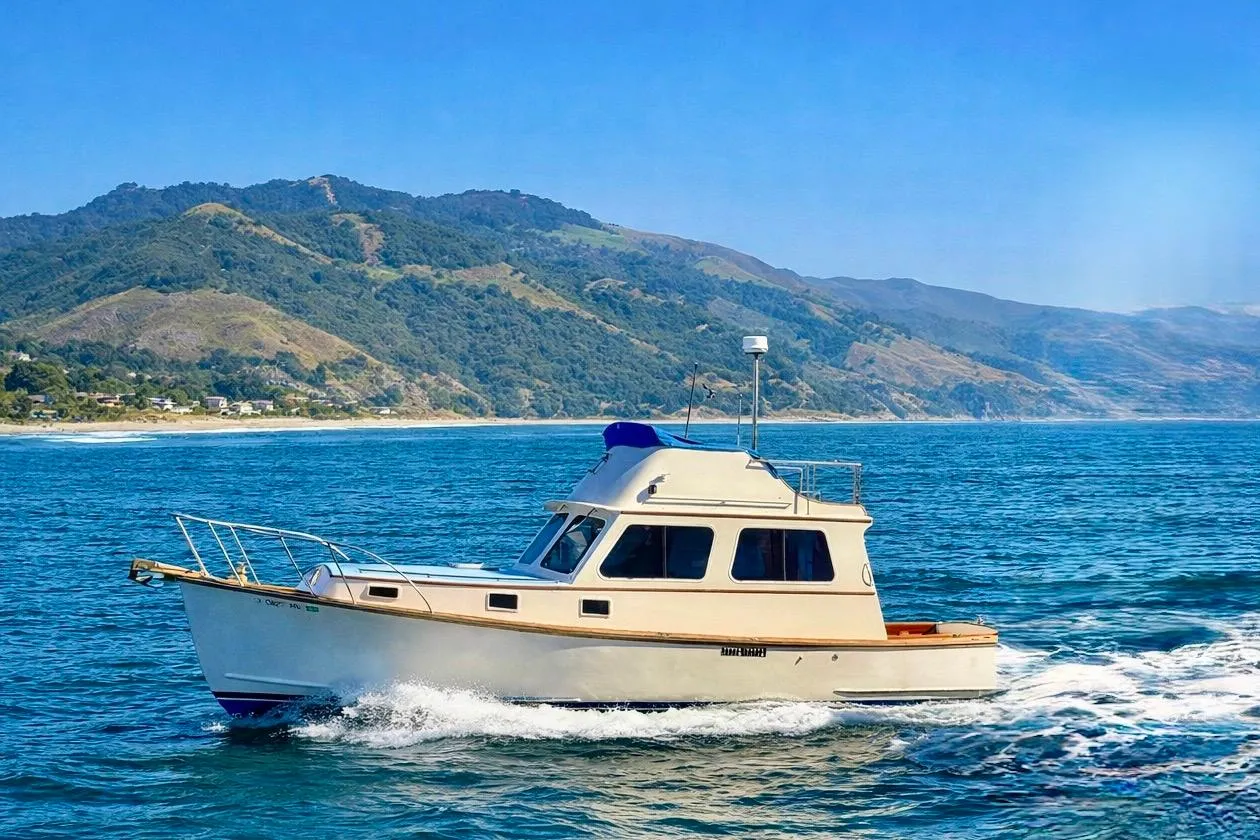 1982 Jarvis Newman Flybridge Cruiser sailing near scenic coastal mountains.