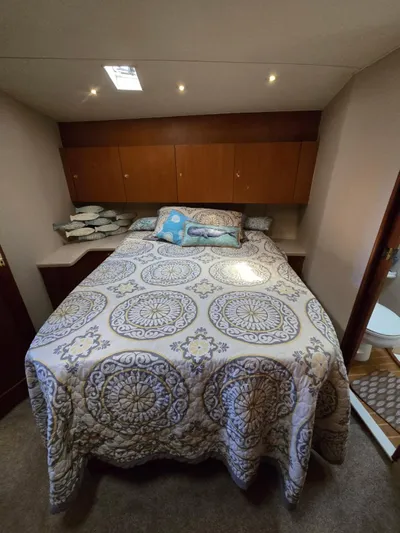  Yacht Photos Pics Cozy bedroom in 1999 Ocean Yachts 48 Super Sport with patterned bedding and wooden cabinets.