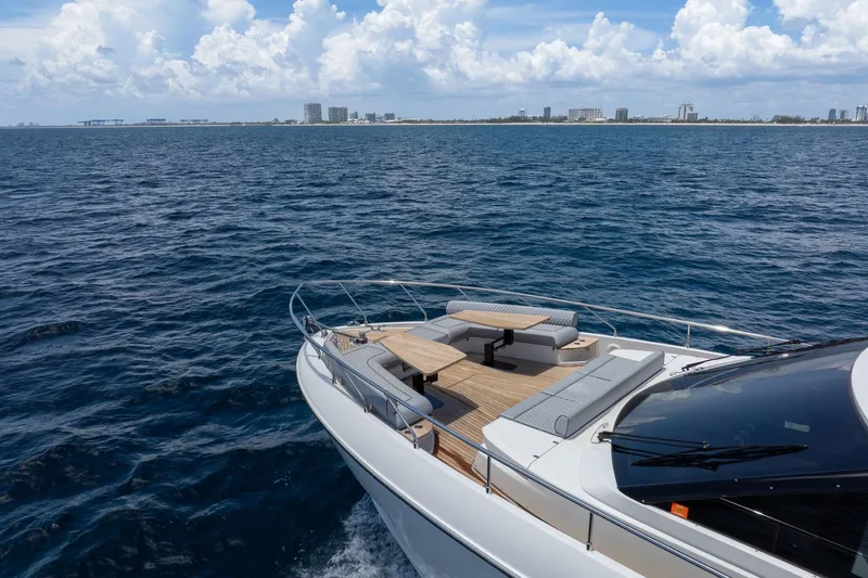  Yacht Photos Pics Luxurious 2022 Ferretti Yachts 670 cruising on open sea with city skyline in background.
