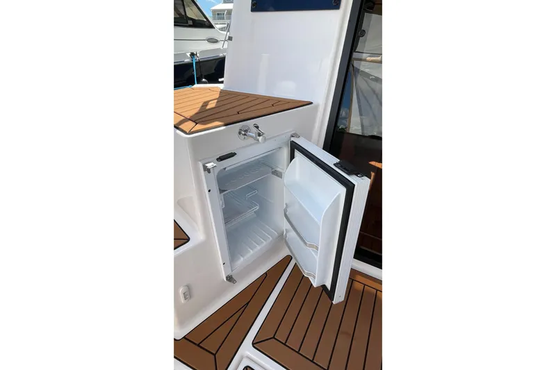  Yacht Photos Pics 2025 Ranger Tugs R-27 Seakeeper Ride with open onboard refrigerator, showcasing teak flooring.