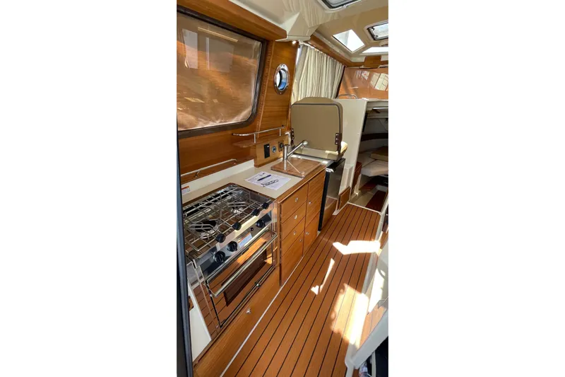  Yacht Photos Pics 2025 Ranger Tugs R-27 Seakeeper Ride interior with wood finish and compact kitchen.