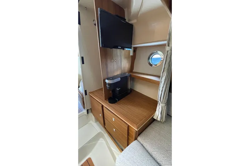 Yacht Photos Pics 2025 Ranger Tugs R-27 Seakeeper Ride interior with TV, coffee maker, and porthole.