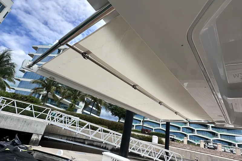 M2o Yacht Photos Pics 2024 Fjord 53 XL yacht with extended sunshade at marina, modern architecture in background.