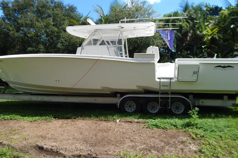  Yacht Photos Pics 2013 Invincible 42 Open Fisherman boat on trailer, surrounded by lush greenery.