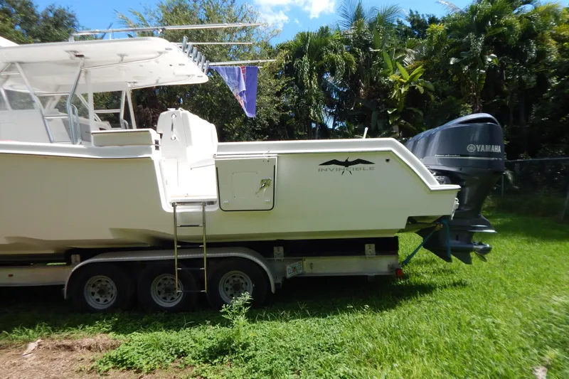  Yacht Photos Pics 2013 Invincible 42 Open Fisherman boat on trailer, surrounded by lush greenery.