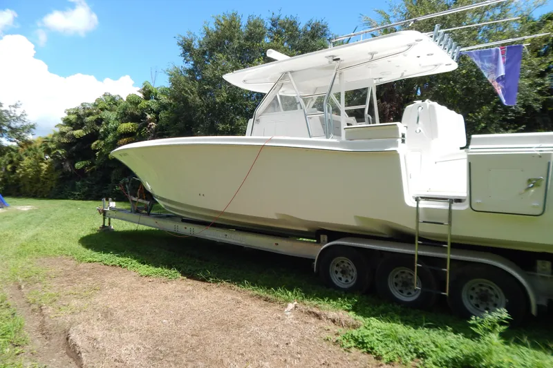  Yacht Photos Pics 2013 Invincible 42 Open Fisherman boat on trailer, parked on grass.