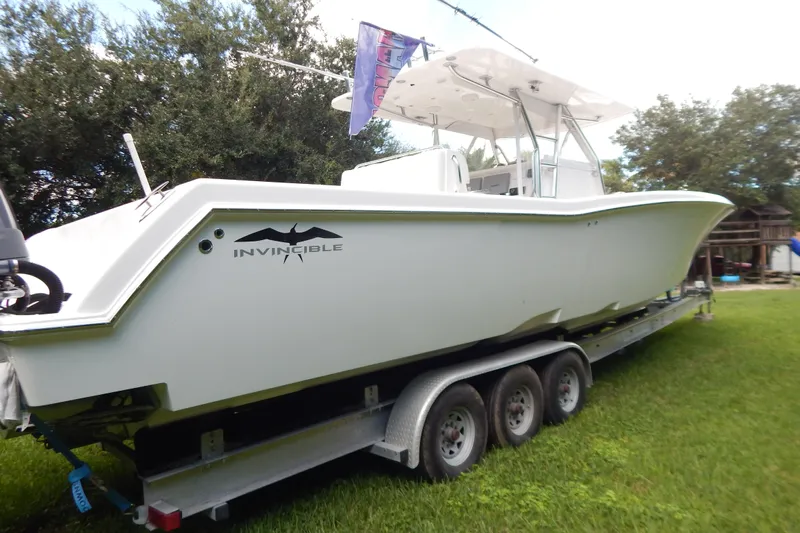  Yacht Photos Pics 2013 Invincible 42 Open Fisherman boat on trailer, parked on grass.