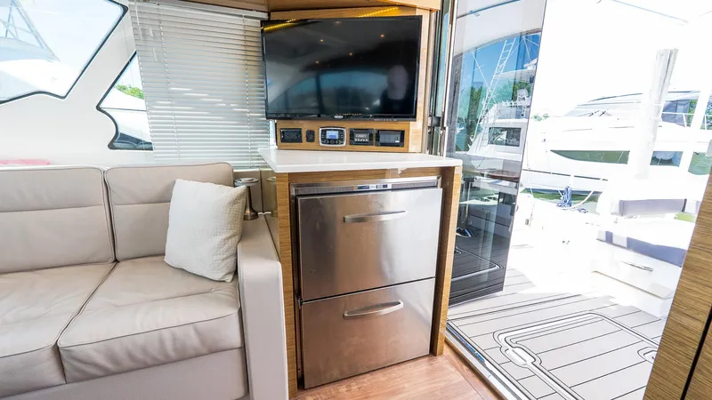 Belle Yacht Photos Pics Interior of 2018 Cruisers Yachts 50 Cantius with TV, sofa, and stainless steel appliances.