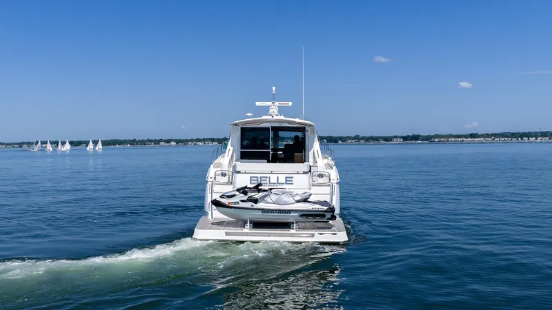 Belle Yacht Photos Pics 2018 Cruisers Yachts 50 Cantius on water with jet ski, sailboats in background.