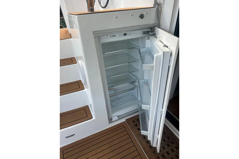 Bolubo Yacht Photos Pics Open refrigerator on 2019 Lagoon 42 yacht, showcasing interior shelves and wooden flooring.