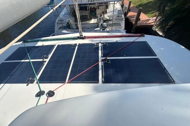 Bolubo Yacht Photos Pics 2019 Lagoon 42 catamaran with solar panels on deck, docked near other boats.