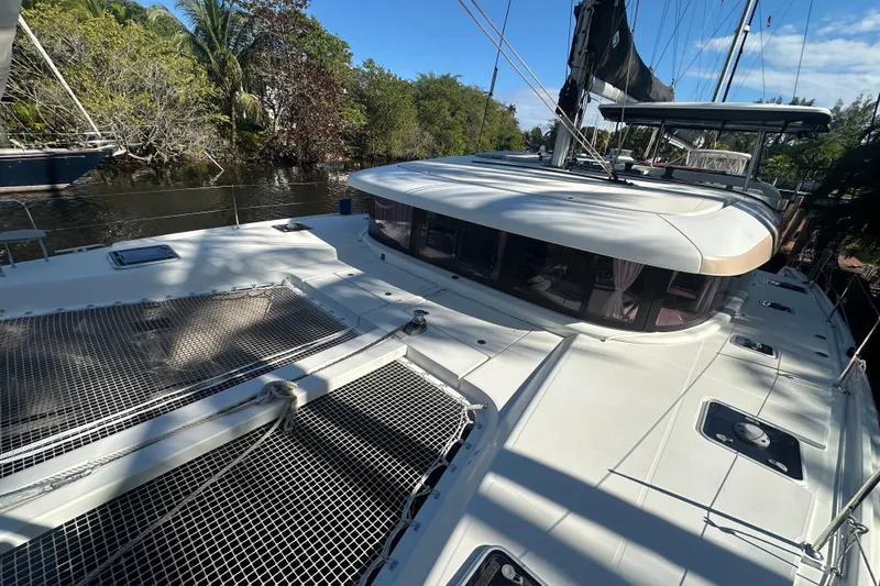 Bolubo Yacht Photos Pics 2019 Lagoon 42 catamaran docked by lush greenery and calm waters.