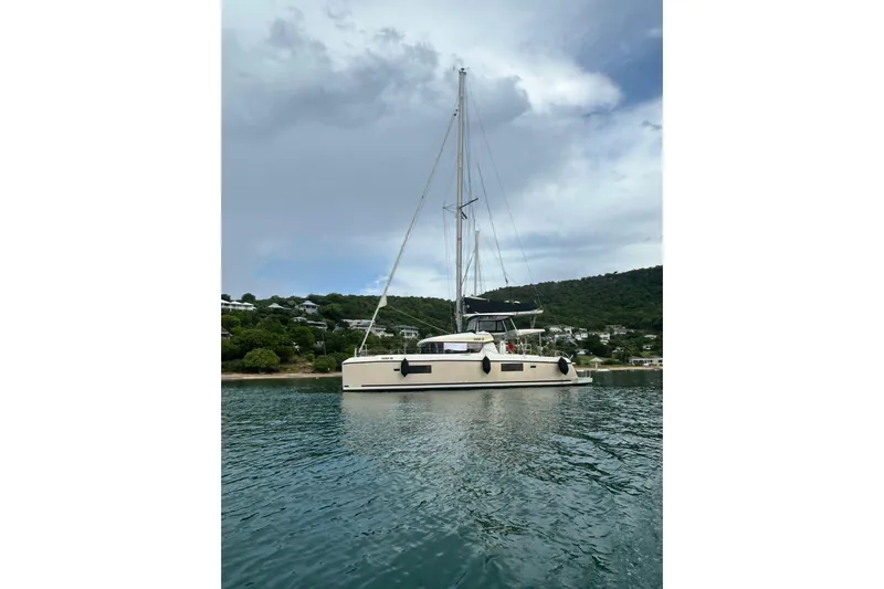 Bolubo Yacht Photos Pics 2019 Lagoon 42 catamaran anchored in serene waters with lush hillside backdrop.