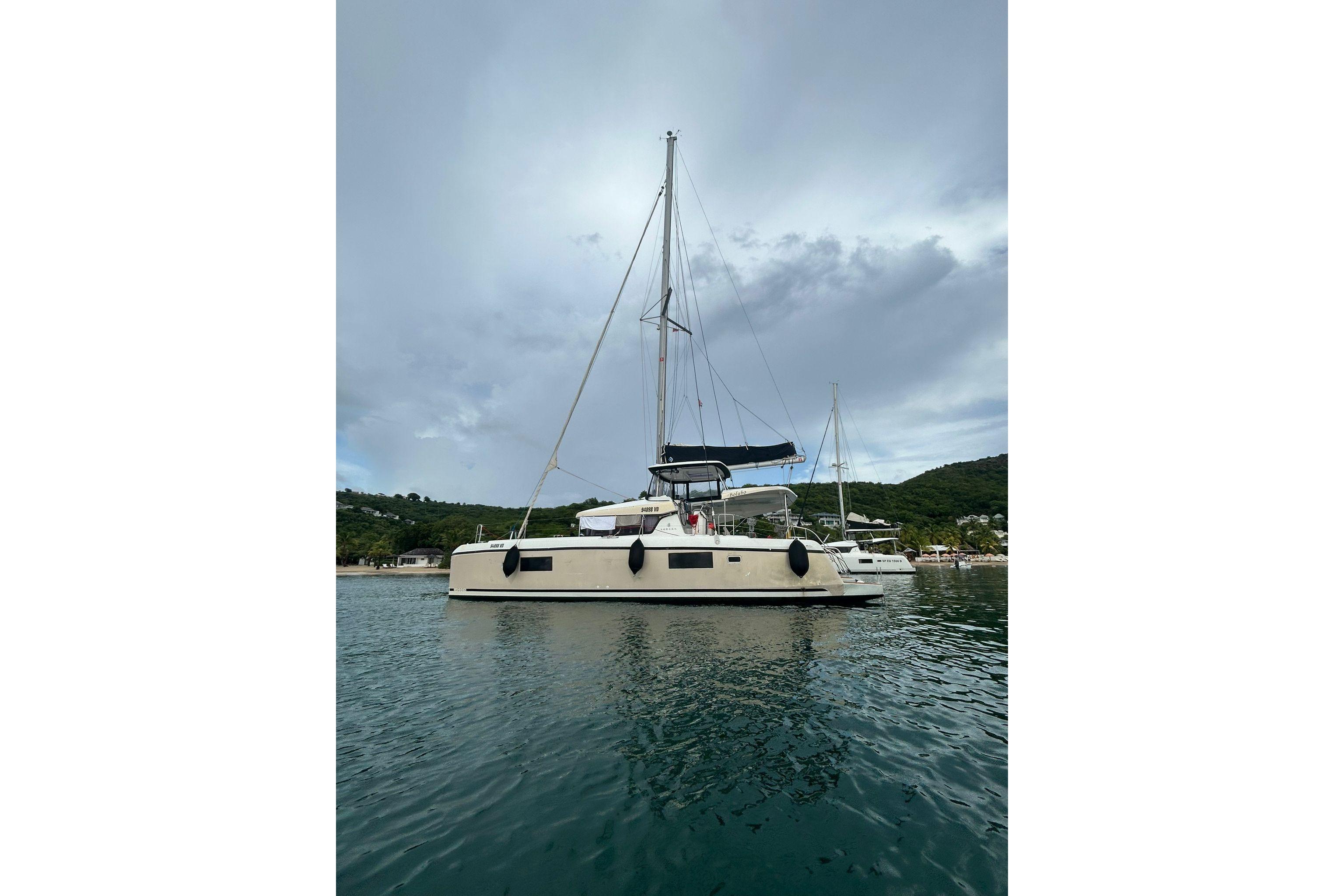 2019 Lagoon 42 catamaran anchored in calm waters, with scenic background.