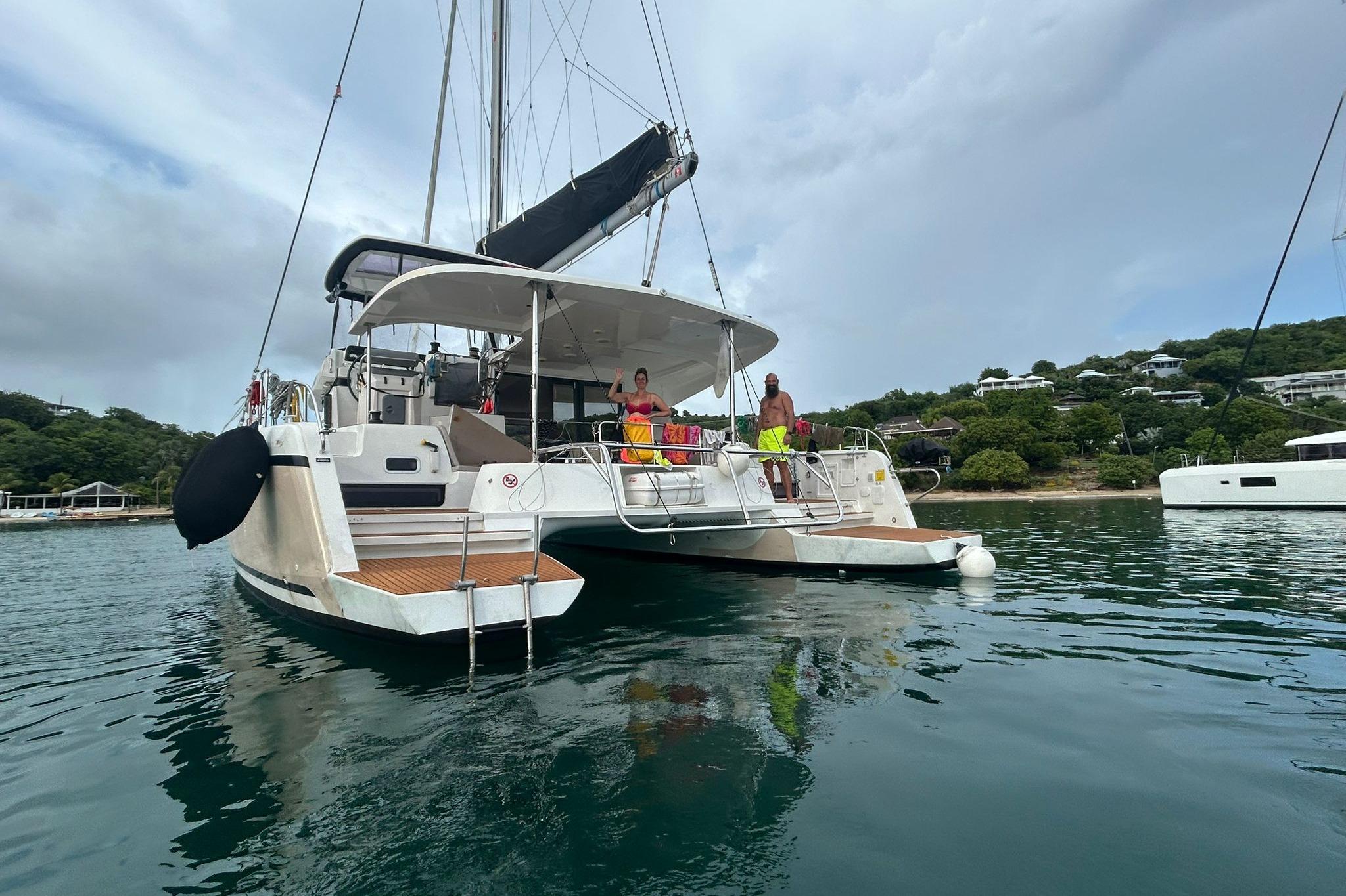 2019 Lagoon 42 catamaran anchored in scenic bay with people on deck.