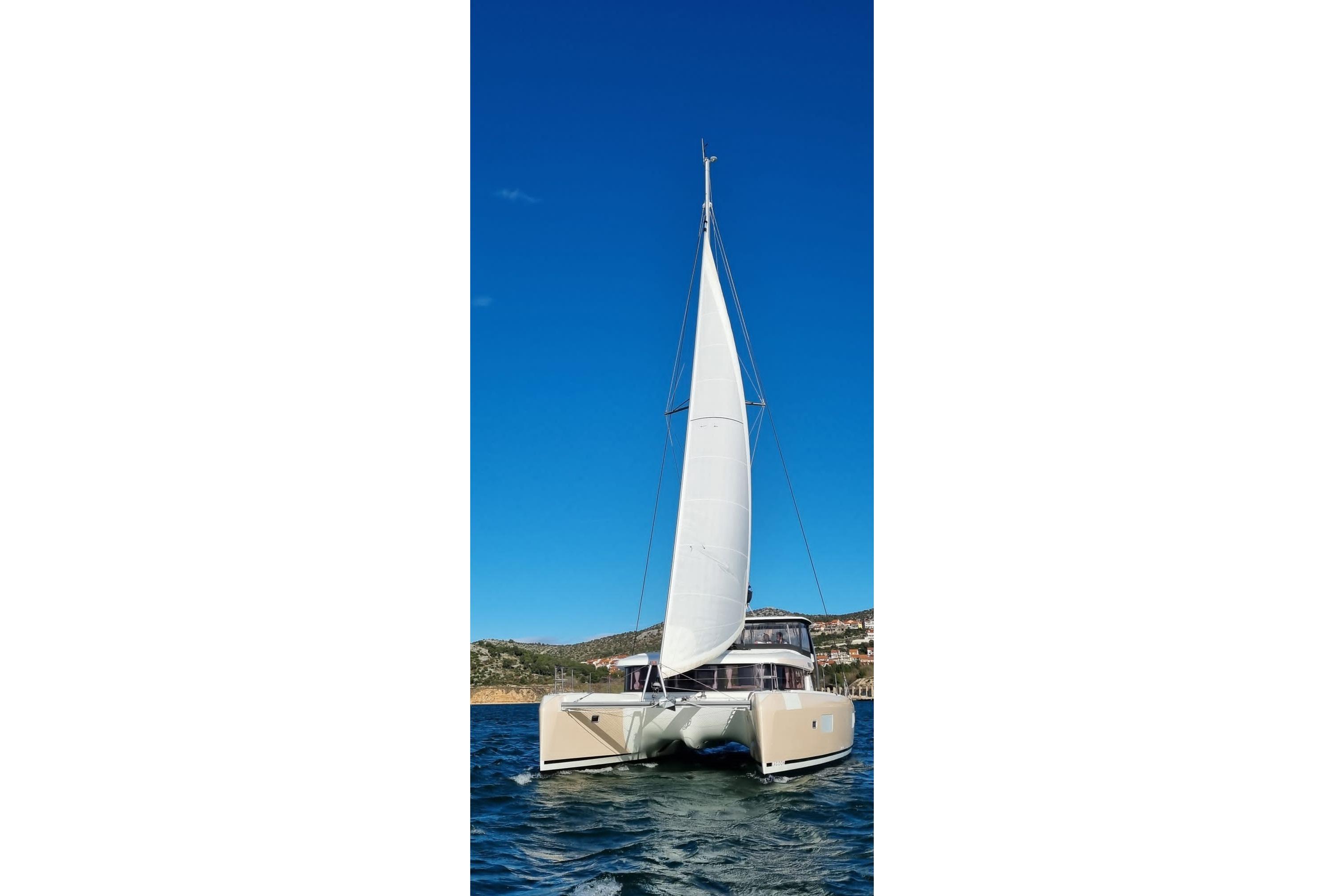 2019 Lagoon 42 catamaran sailing on clear blue waters under a bright sky.