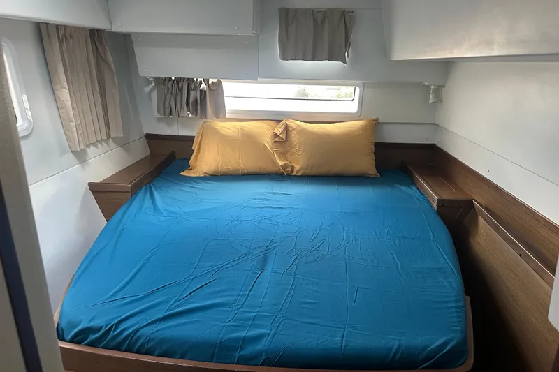 Bolubo Yacht Photos Pics Cozy cabin bedroom in 2019 Lagoon 42 catamaran with blue bedding and yellow pillows.