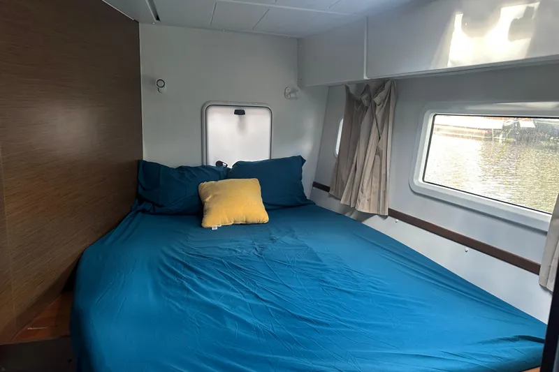 Bolubo Yacht Photos Pics Cozy cabin interior of 2019 Lagoon 42 catamaran with blue bedding and window view.