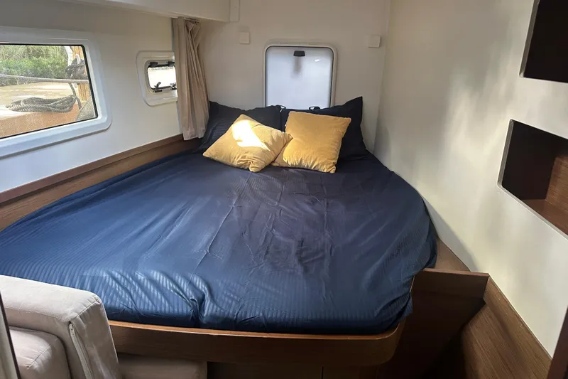 Bolubo Yacht Photos Pics Cozy cabin interior of 2019 Lagoon 42 catamaran with blue bedding and yellow pillows.