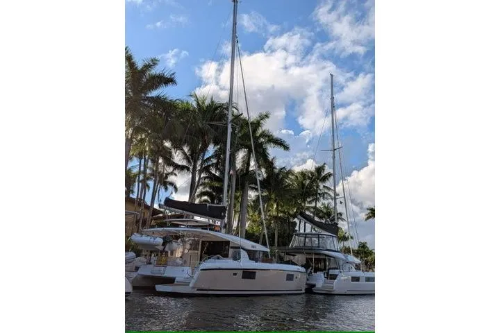 Bolubo Yacht Photos Pics 2019 Lagoon 42 catamarans docked by palm trees under a blue sky.