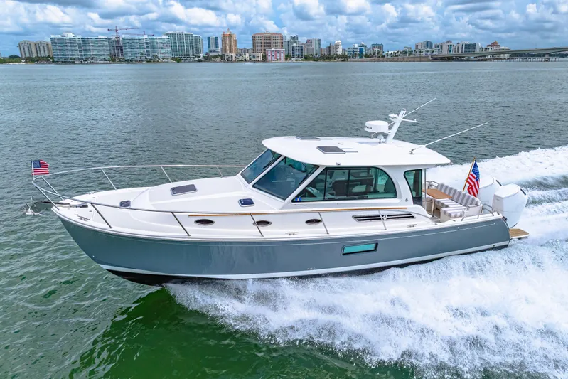  Yacht Photos Pics 2024 Back Cove 39O yacht cruising on water with city skyline in background.
