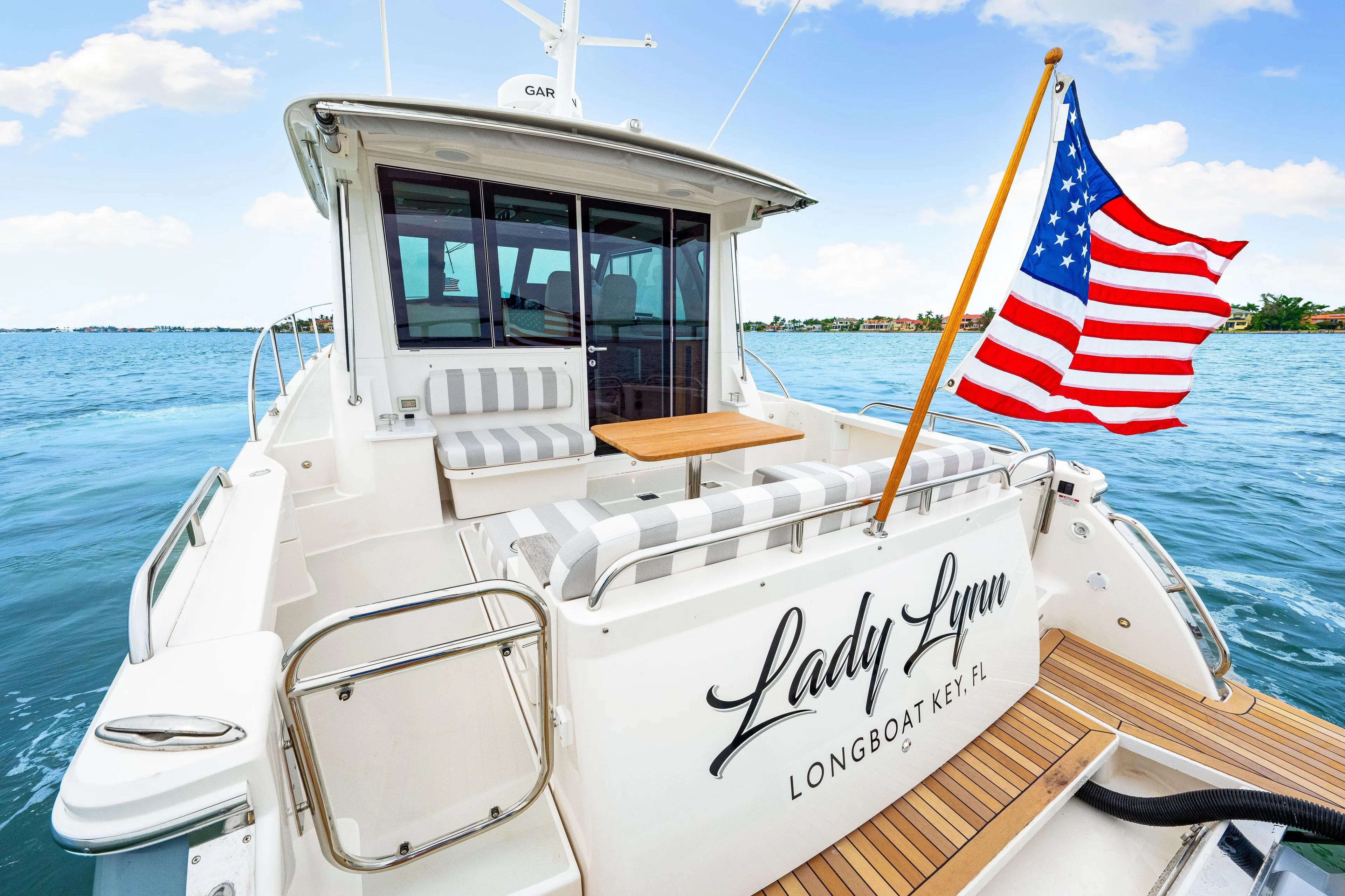  Yacht Photos Pics 2024 Back Cove 39O yacht with American flag, docked at sea, featuring elegant seating and wood accents.