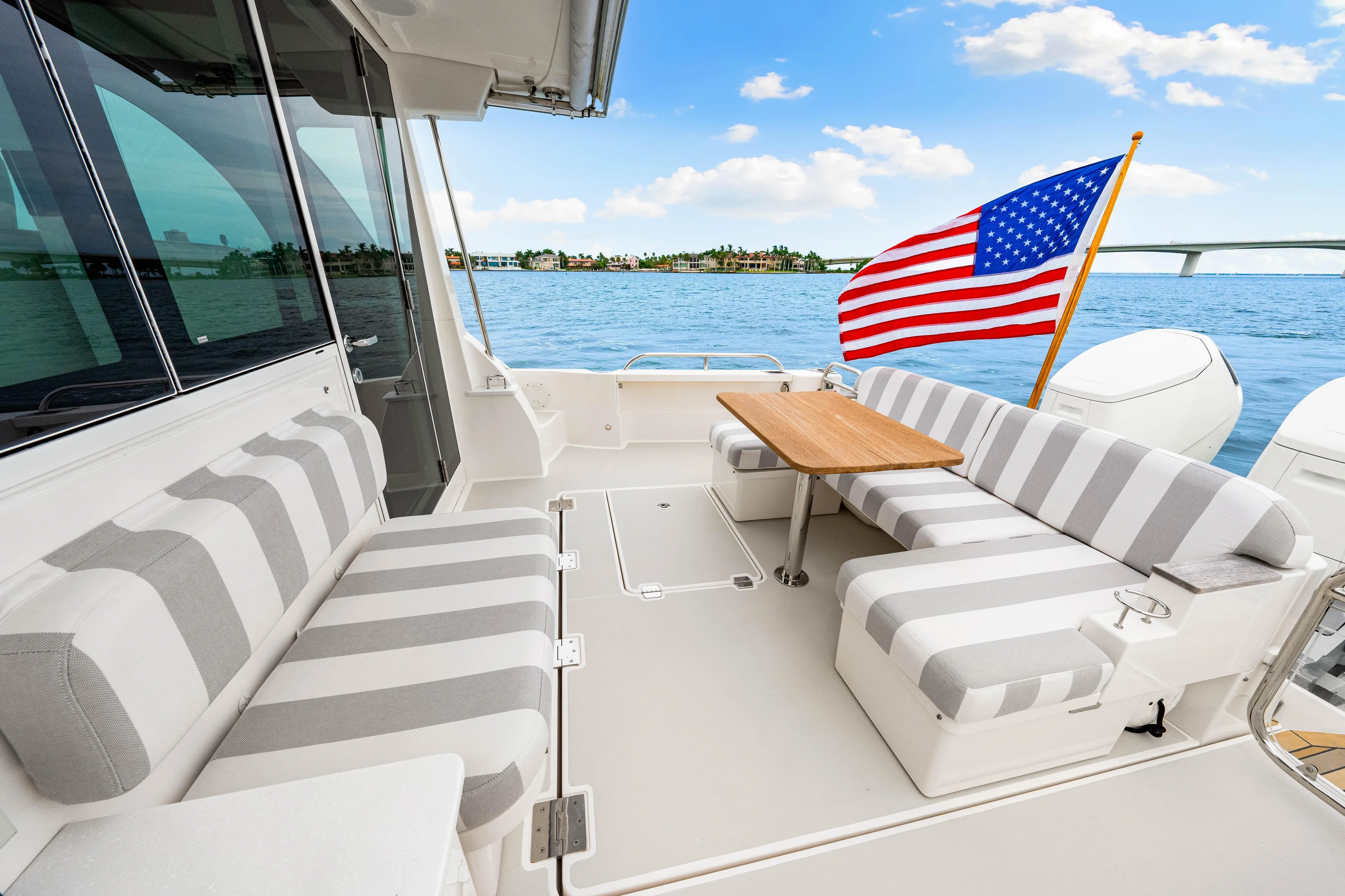  Yacht Photos Pics 2024 Back Cove 39O yacht with striped seating, wooden table, and American flag on open water.