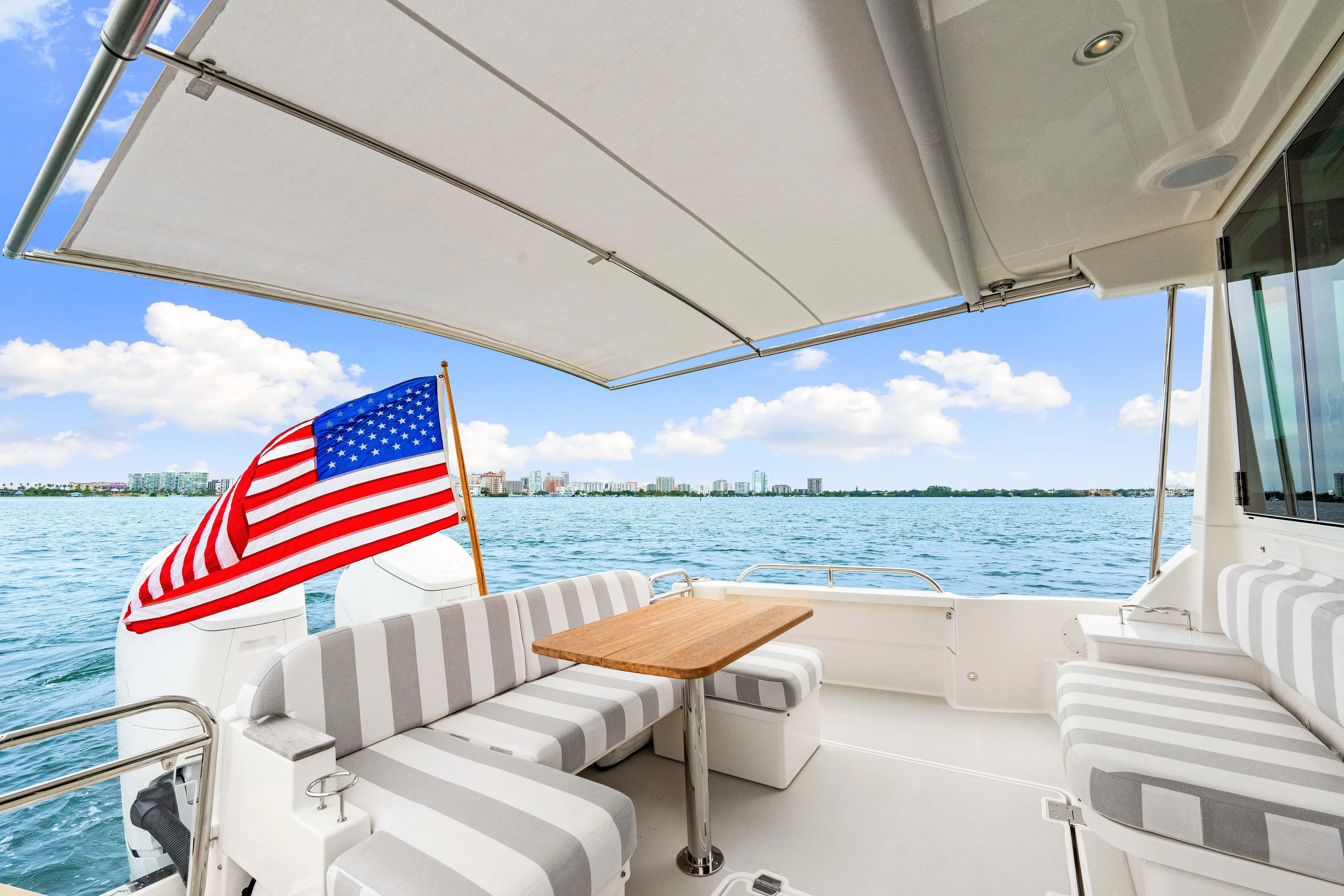  Yacht Photos Pics 2024 Back Cove 39O yacht deck with American flag, striped seating, and ocean view.