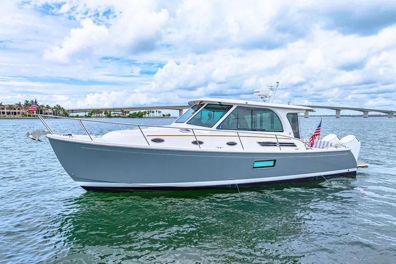  Yacht Photos Pics 2024 Back Cove 39O boat on water, sleek design, bridge in background, partly cloudy sky.