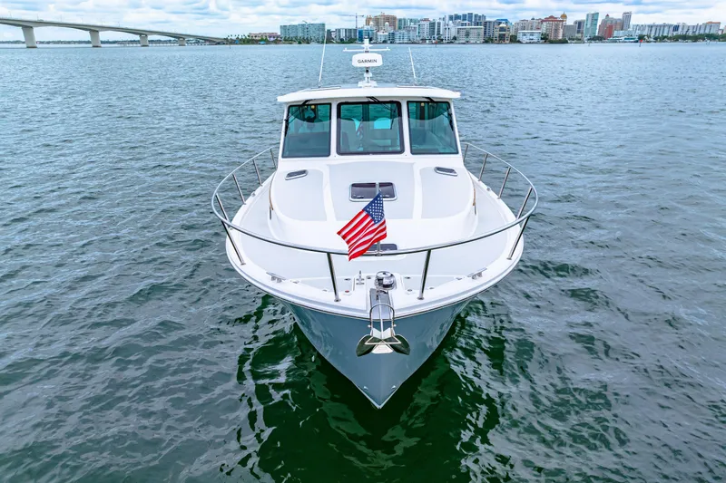  Yacht Photos Pics 2024 Back Cove 39O boat on water, American flag, cityscape background.
