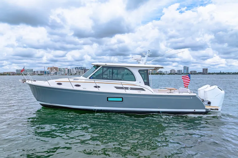  Yacht Photos Pics 2024 Back Cove 39O boat on water, city skyline in background, cloudy sky.