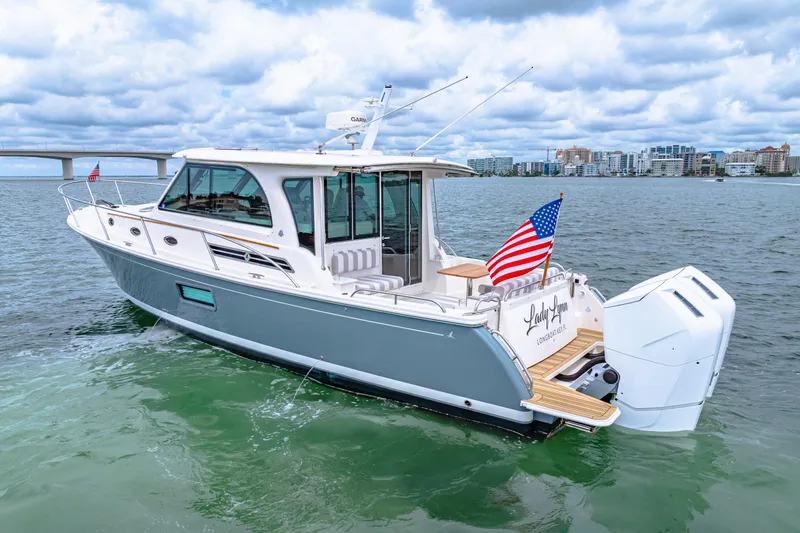  Yacht Photos Pics 2024 Back Cove 39O yacht on water, American flag, cityscape background.