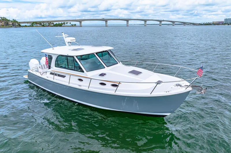  Yacht Photos Pics 2024 Back Cove 39O boat cruising on water with bridge in background.